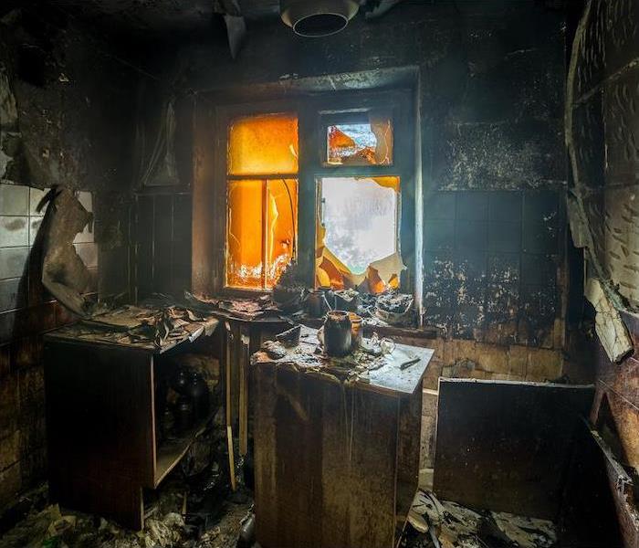 Photo of a Fire Damaged Kitchen with soot covering the walls, and burnt cabinetry.