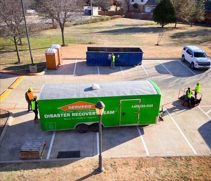 SERVPRO green Disaster Recovery truck trailer parked outside of a property restoration project with four workers around it